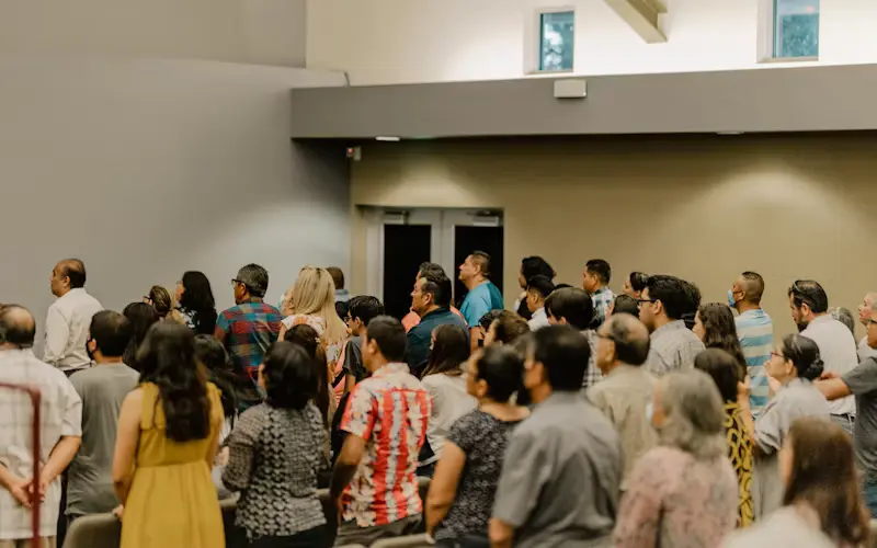 Gran multitud de personas de pie reunidas en un salón de actos.